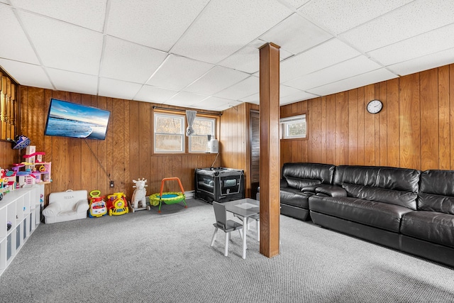 carpeted living room with a paneled ceiling and wood walls