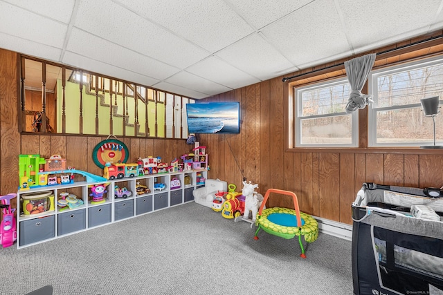 game room featuring carpet floors, a drop ceiling, and wooden walls