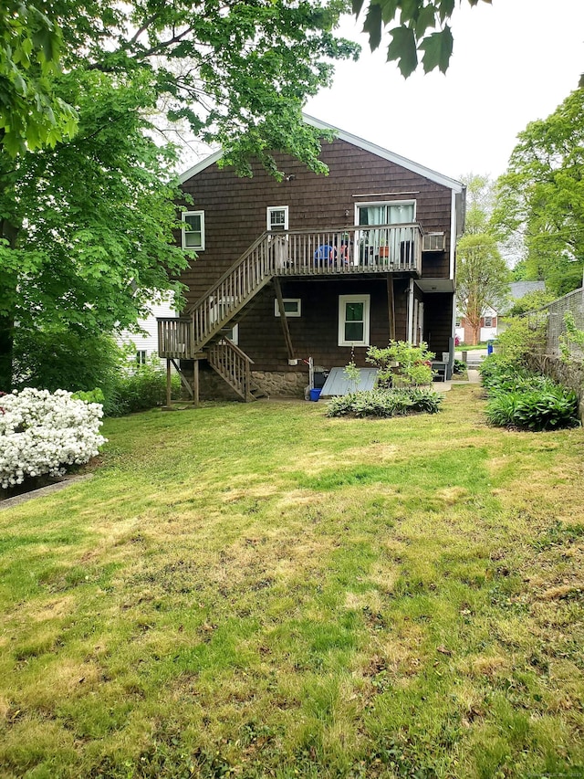 rear view of house with a wooden deck, a lawn, and stairs