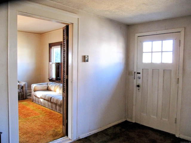 foyer with a healthy amount of sunlight, dark colored carpet, and a textured ceiling