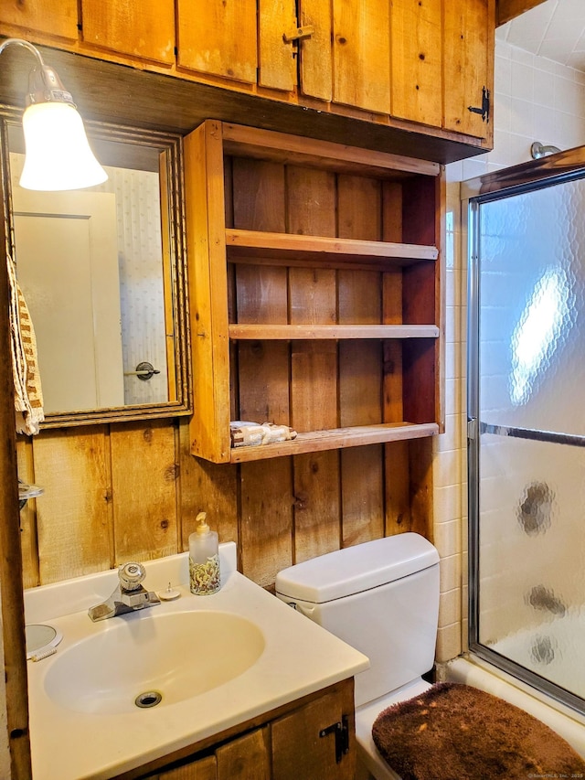 bathroom with a shower with door, toilet, wood walls, and vanity