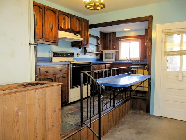 kitchen featuring under cabinet range hood, range with electric stovetop, and brown cabinetry