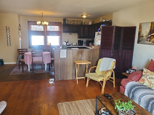 kitchen featuring a chandelier, pendant lighting, light countertops, a peninsula, and dark wood-style flooring