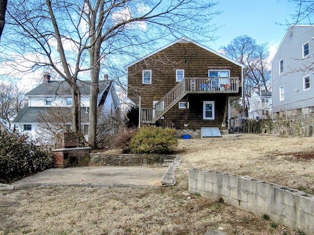 rear view of house with a wooden deck, a fireplace, and stairs