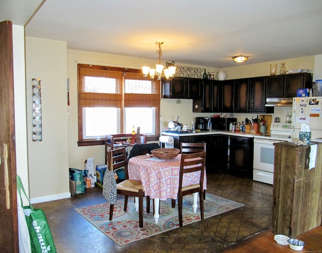 kitchen featuring under cabinet range hood, decorative light fixtures, white appliances, baseboards, and a chandelier