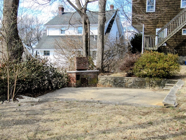 view of yard featuring stairway, an outdoor fireplace, and a patio area