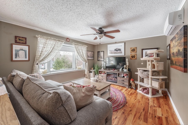 living area featuring ceiling fan, ornamental molding, wood finished floors, a textured ceiling, and a wall mounted AC