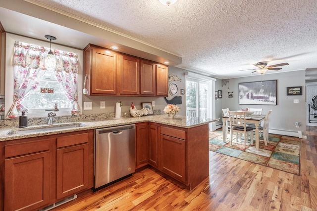 kitchen featuring a peninsula, a sink, dishwasher, light wood finished floors, and brown cabinetry