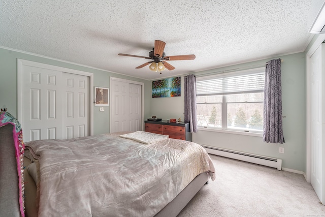 bedroom with a textured ceiling, a baseboard heating unit, light carpet, multiple closets, and ornamental molding