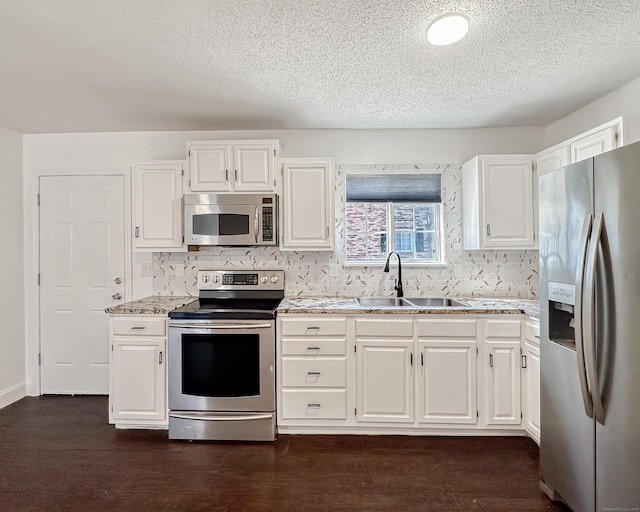 kitchen with tasteful backsplash, dark wood-type flooring, appliances with stainless steel finishes, white cabinetry, and a sink