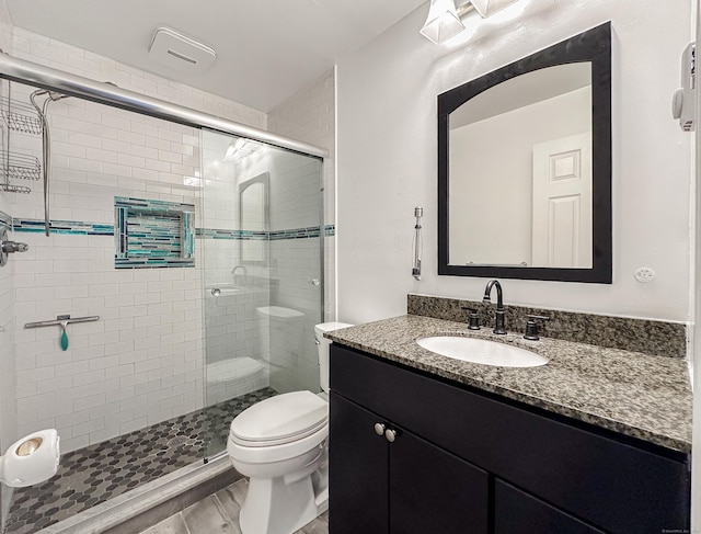 bathroom featuring vanity, a shower stall, and toilet