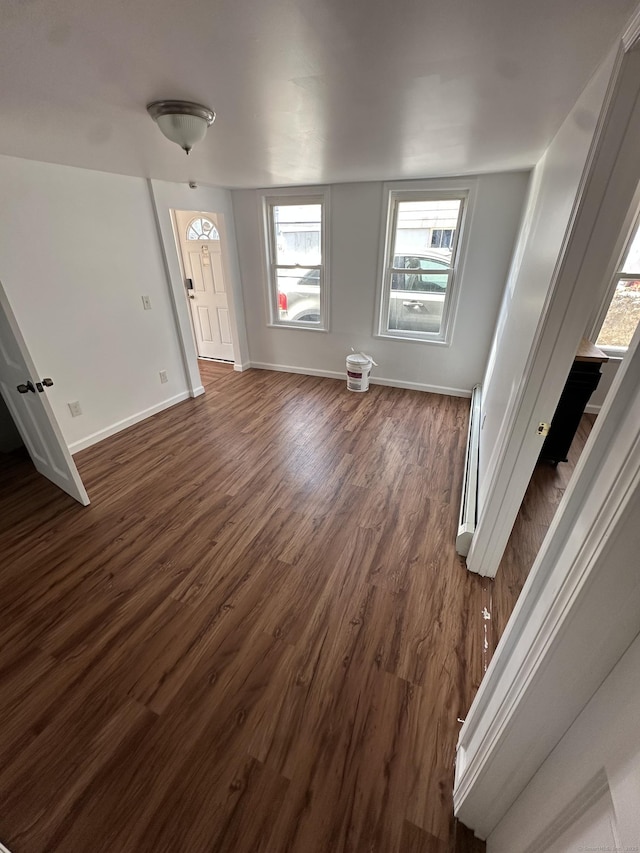 empty room featuring dark wood finished floors, baseboards, and a baseboard radiator