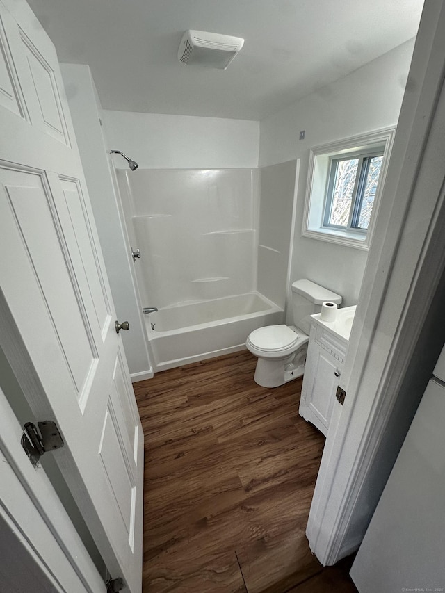 bathroom with vanity, wood finished floors, shower / bathtub combination, and toilet