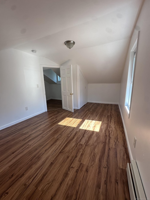 additional living space with vaulted ceiling, dark wood-style floors, and baseboards