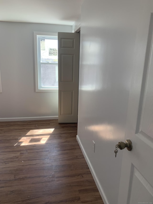 empty room featuring dark wood finished floors and baseboards