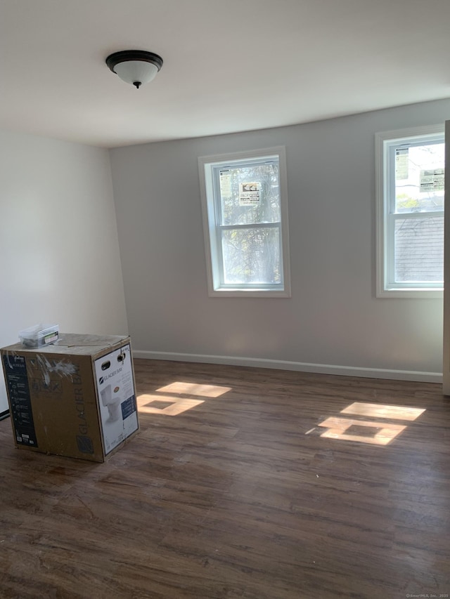 spare room with dark wood finished floors and baseboards