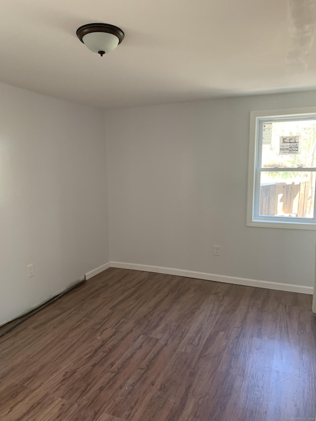 unfurnished room with dark wood finished floors and baseboards