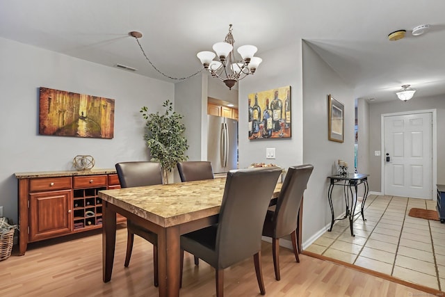 dining area with light wood-type flooring, visible vents, baseboards, and an inviting chandelier