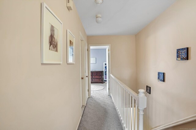 hallway with an upstairs landing and light colored carpet