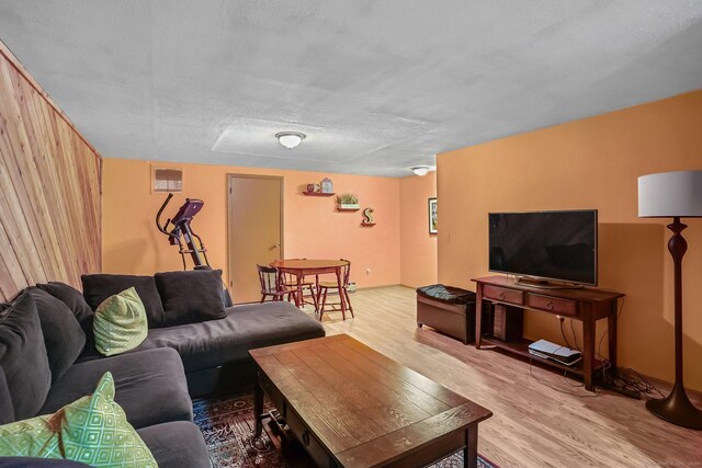 living room with a textured ceiling, visible vents, and light wood-style flooring