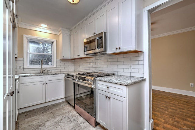 kitchen with a sink, ornamental molding, backsplash, and stainless steel appliances