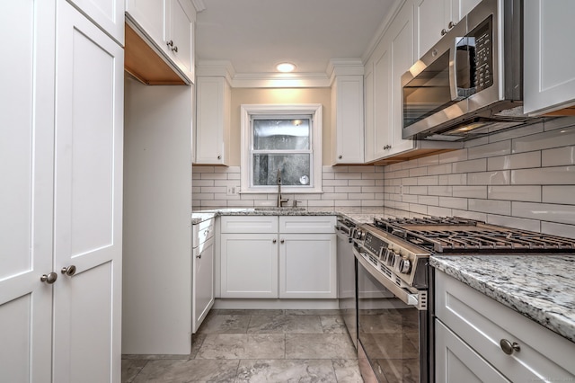 kitchen featuring a sink, light stone counters, white cabinetry, stainless steel appliances, and decorative backsplash