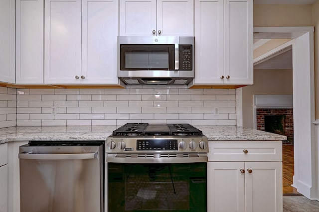 kitchen featuring light stone counters, decorative backsplash, appliances with stainless steel finishes, and white cabinetry