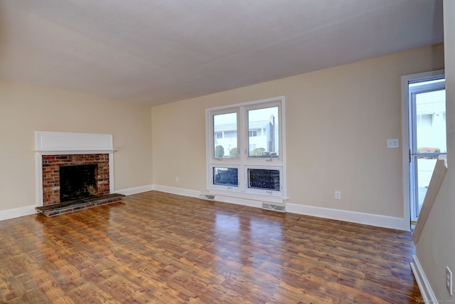 unfurnished living room featuring visible vents, a fireplace, baseboards, and wood finished floors