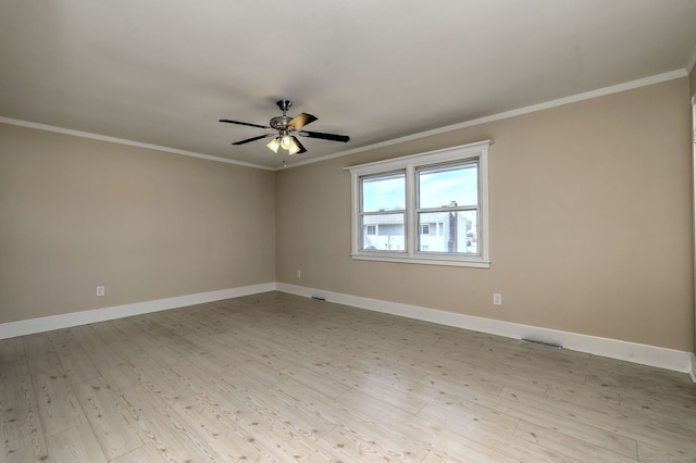 spare room featuring light wood finished floors, visible vents, crown molding, ceiling fan, and baseboards