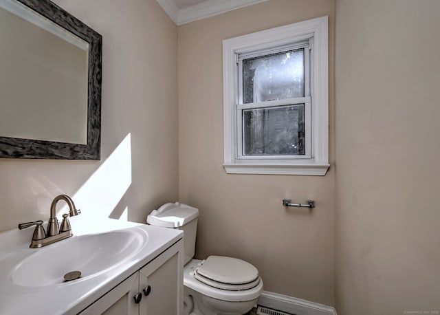 half bathroom with crown molding, toilet, vanity, and baseboards