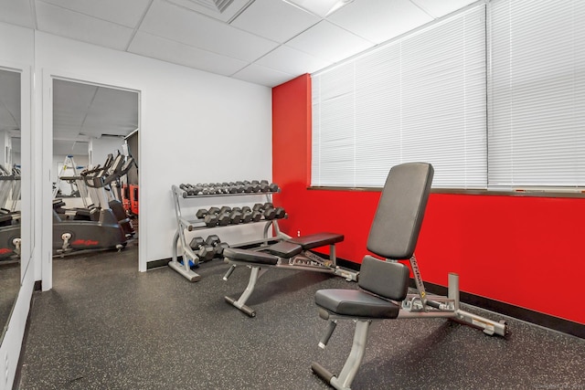 workout area featuring a paneled ceiling and baseboards