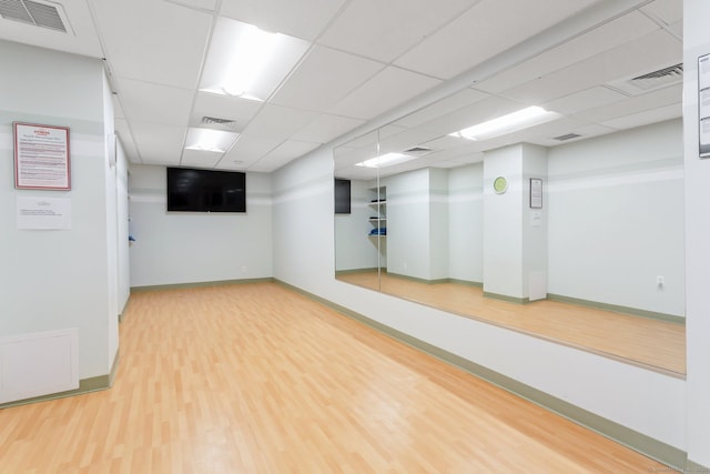 exercise area with wood finished floors, visible vents, and baseboards