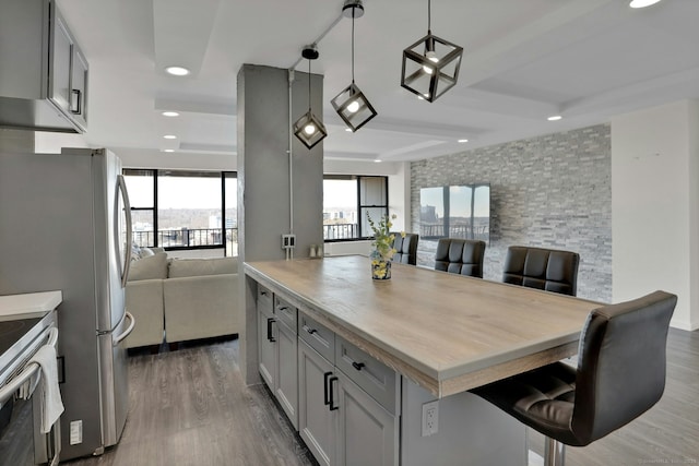 kitchen featuring a breakfast bar area, open floor plan, wood finished floors, and light countertops