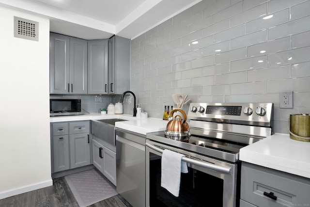 kitchen with gray cabinets, visible vents, stainless steel appliances, and decorative backsplash