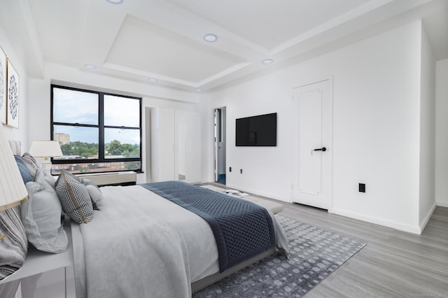 bedroom featuring coffered ceiling, wood finished floors, and baseboards