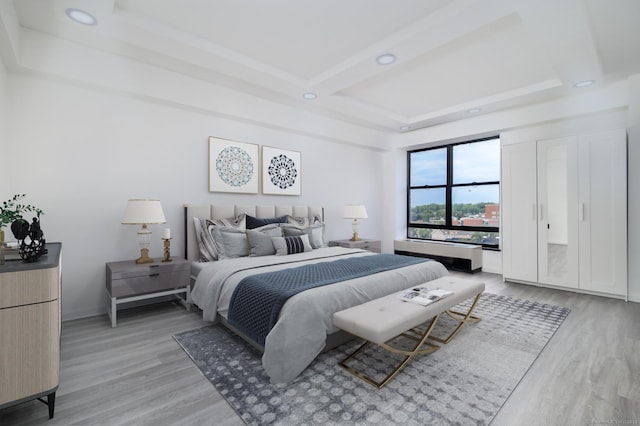 bedroom with baseboards, light wood-type flooring, a raised ceiling, and recessed lighting