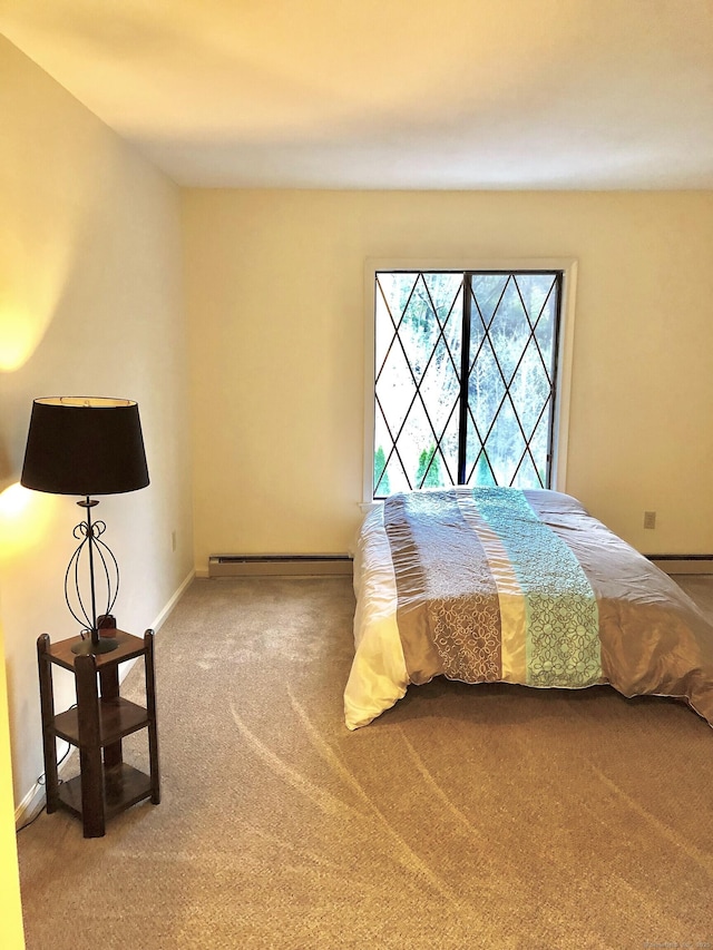 bedroom featuring a baseboard heating unit, carpet floors, and baseboards