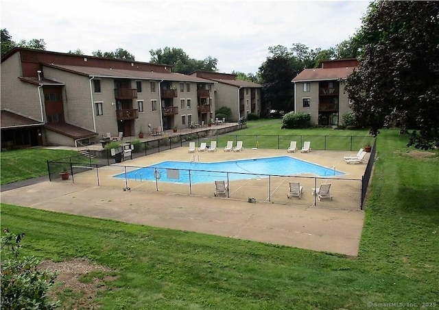 community pool with a patio area, a yard, and fence