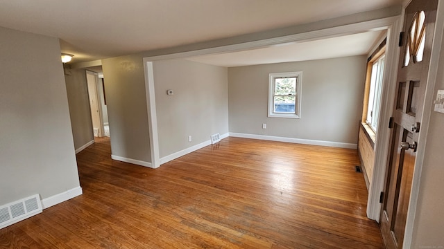 empty room featuring visible vents, baseboards, and wood finished floors