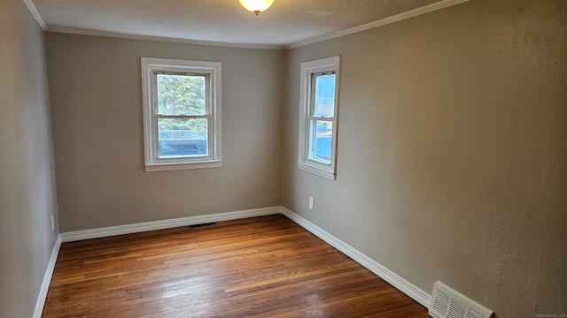 unfurnished room with ornamental molding, wood finished floors, visible vents, and baseboards