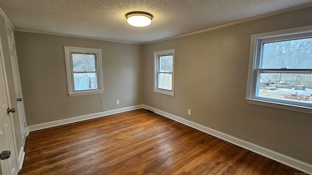 unfurnished room with a healthy amount of sunlight, a textured ceiling, baseboards, and wood finished floors