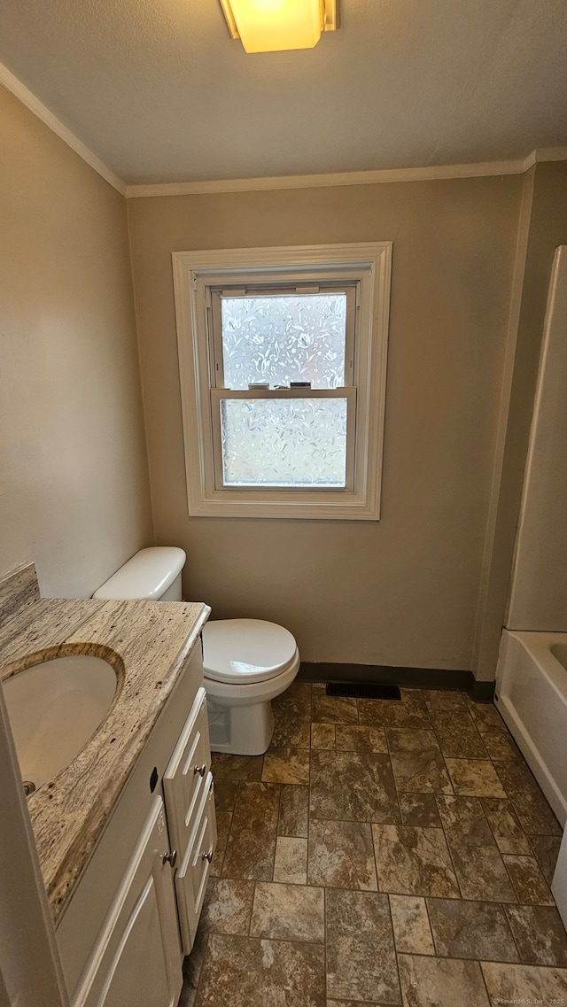 bathroom featuring toilet, stone finish flooring, ornamental molding, and vanity