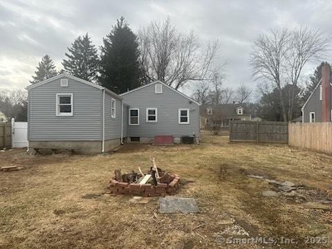 rear view of property with a fire pit and fence