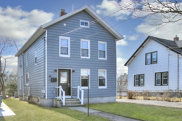 view of front of property featuring a chimney and a front lawn