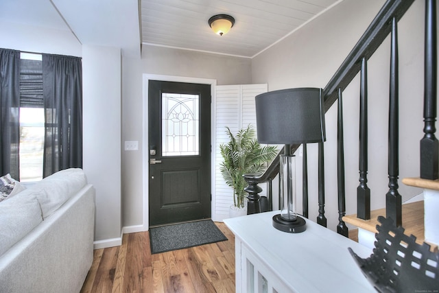 foyer entrance with wood finished floors, baseboards, and stairs