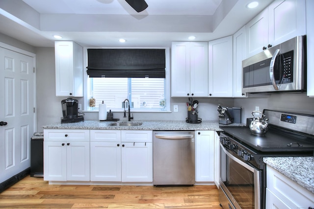 kitchen featuring white cabinetry, light wood-style flooring, appliances with stainless steel finishes, and a sink