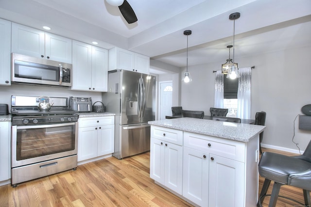 kitchen with light stone counters, pendant lighting, appliances with stainless steel finishes, white cabinetry, and light wood-type flooring