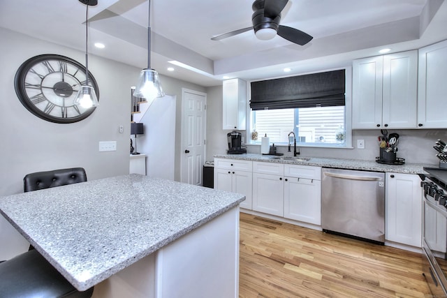 kitchen with light wood finished floors, appliances with stainless steel finishes, a sink, and white cabinetry