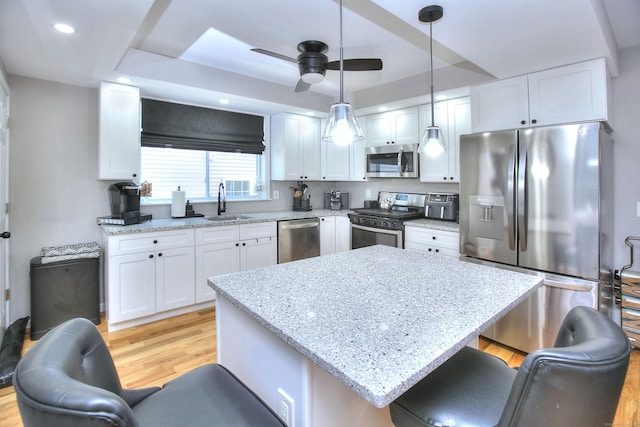 kitchen featuring a breakfast bar area, appliances with stainless steel finishes, light wood-style floors, white cabinets, and a sink