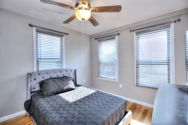 bedroom with ceiling fan, wood finished floors, and baseboards